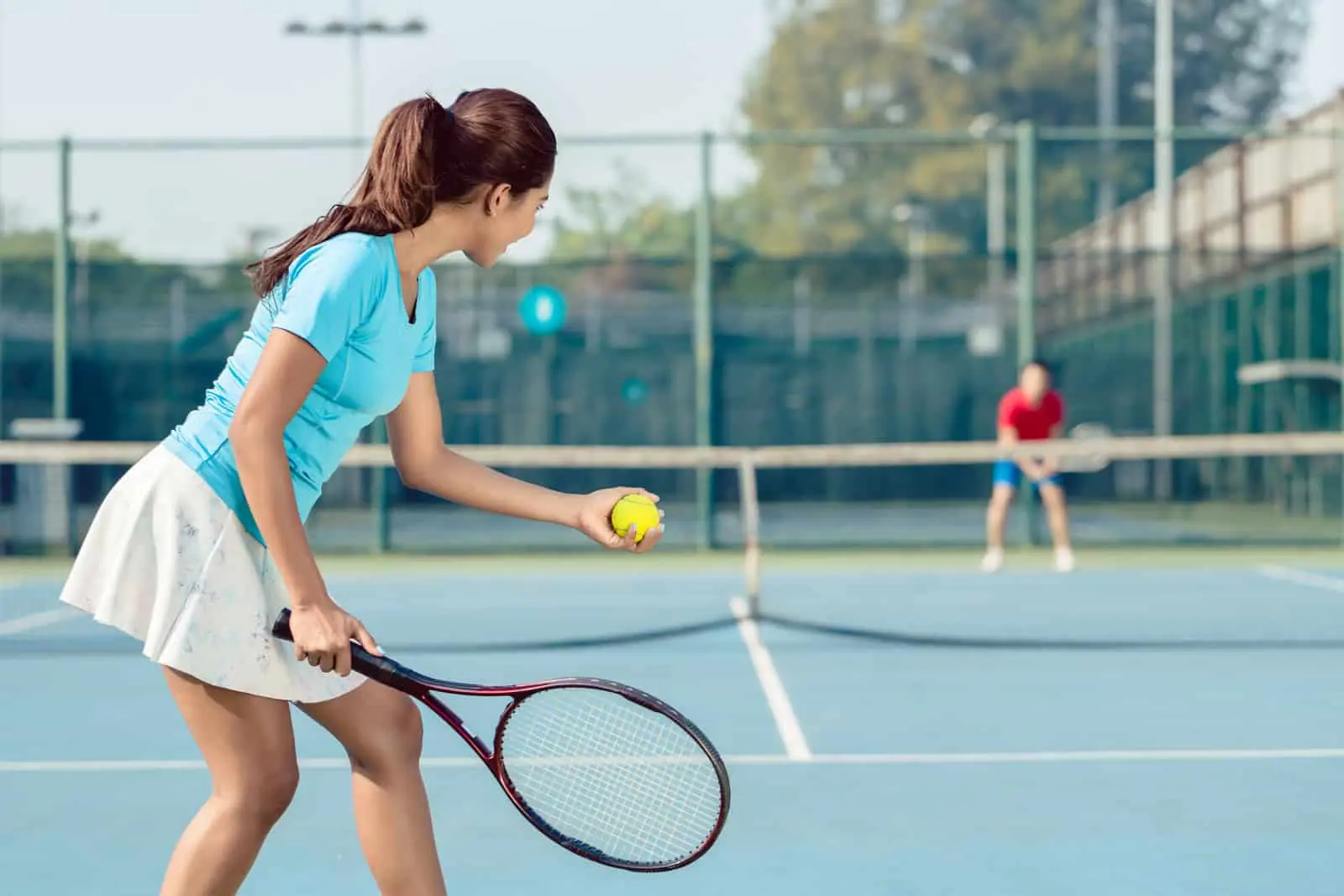 Woman tennis player gets ready to serve on a blue court