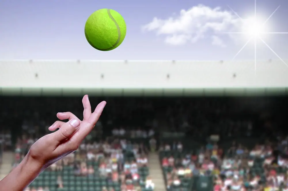 A tennis player tosses a ball to serve