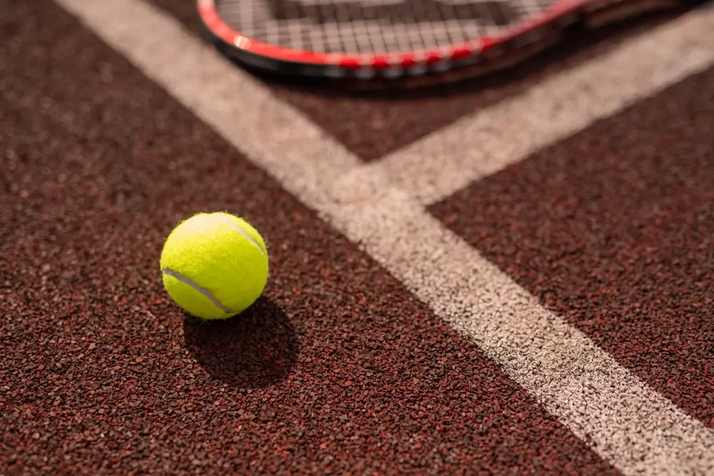 A tennis ball on a red clay court line