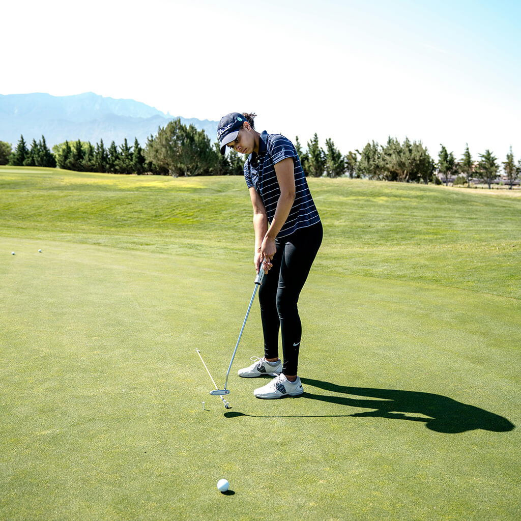 A golfer carefully lines up for a putt on the green, ready for precision
