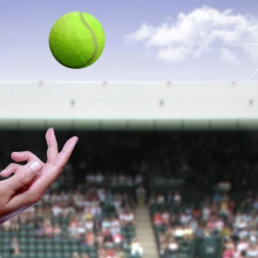 A tennis player tosses a ball to serve